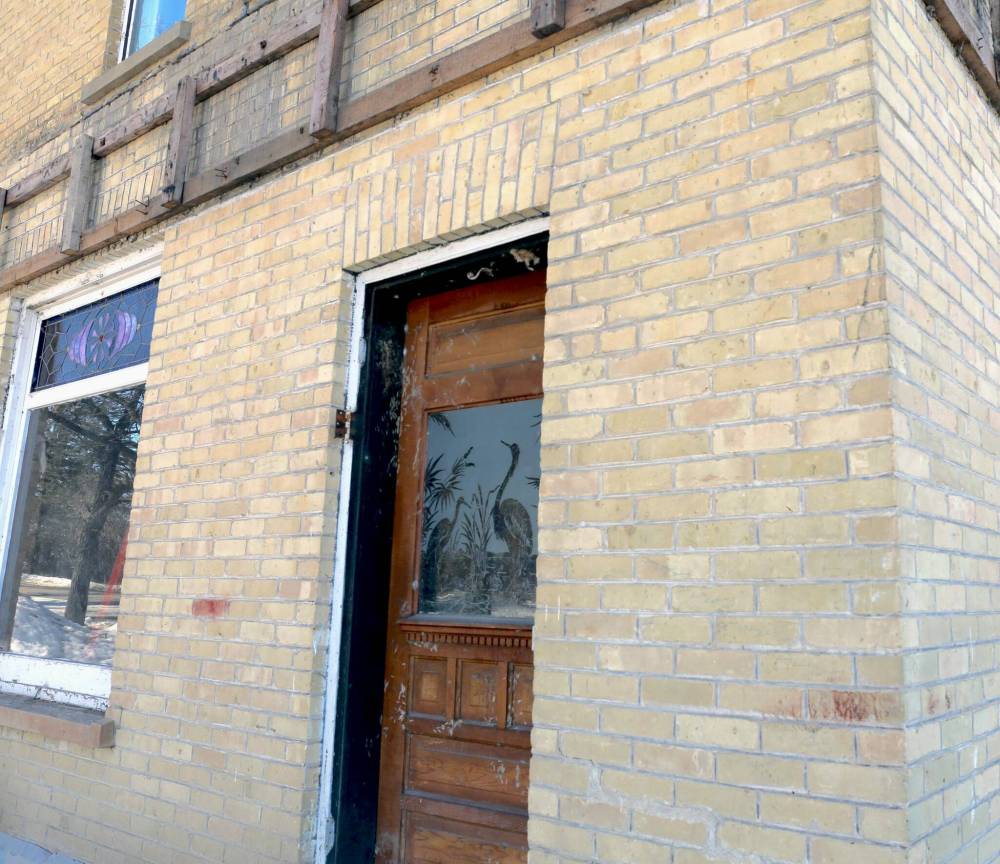 LEFT: Friesen is keeping an etched glass door, and a stained-glass window as accents for the home when it is rebuilt. RIGHT: The house, which neighbours the entrance to Wawanesa, is seen in March. A local retiree, Neil Friesen, has bought the house and plans to build it back to be livable again before putting it up for sale. (Photos by Connor McDowell/Brandon Sun)