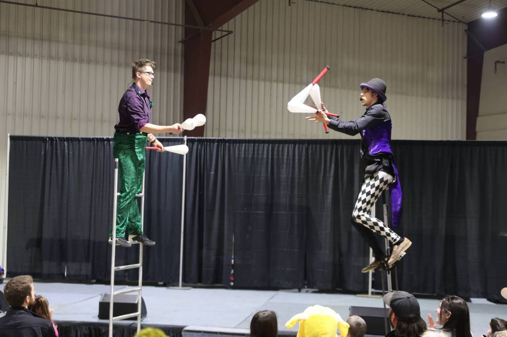 Knife juggler Schuyler Snowdon (left) on an eight-foot acrobatic ladder passes six clubs to lightsaber juggler Matthew McLeod, who is on an eight-foot unicycle during their performance at the Royal Manitoba Winter Fair Friday afternoon. (Abiola Odutola/The Brandon Sun)