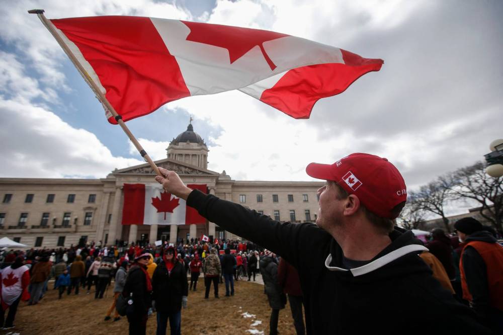 Adam Hannah waves his flag as hundreds of people gather at the legislative grounds in Winnipeg on Sunday for the Rally For Canada. (John Woods/Winnipeg Free Press files)