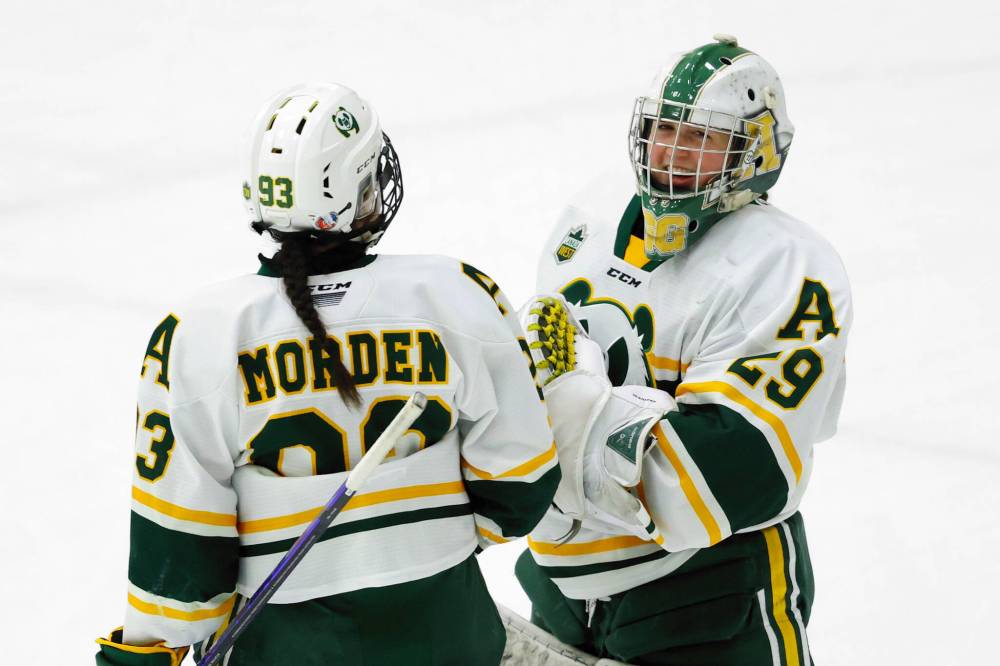 Grace Glover of Boissevain (29) smiles as she is congratulated by her Alberta teammate Jadynn Morden (93) following an 18-save 1-0 shutout victory over Mount Royal at Clare Drake Arena on March 1. (James Maclennan/University of Alberta)