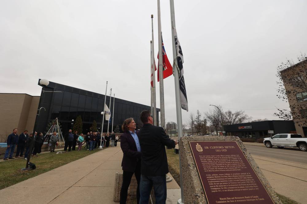 Brandon and District Labour Council first vice-president Brad Broome (right) and Brandon Mayor Jeff Fawcett lower the flag to mark the National Day of Mourning Sunday morning at city hall. The event, attended by about 40 residents, was a tribute to workers who have tragically lost their lives or been injured on the job. (Abiola Odutola/The Brandon Sun)