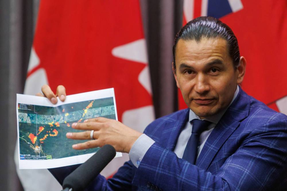Premier Wab Kinew holds up a satellite image of the Flin Flon area that shows where the wildfires are during a wildfire update held at the Manitoba Legislative Building on Friday afternoon. (Mike Deal/Winnipeg Free Press)