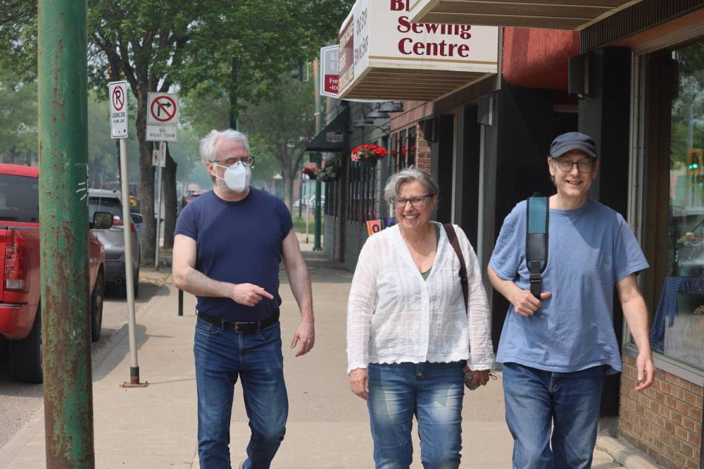 A resident wears a mask as he walks with two others along Princess Ave. on Saturday morning as smoke hangs thick in the air. (Abiola Odutola/The Brandon Sun)