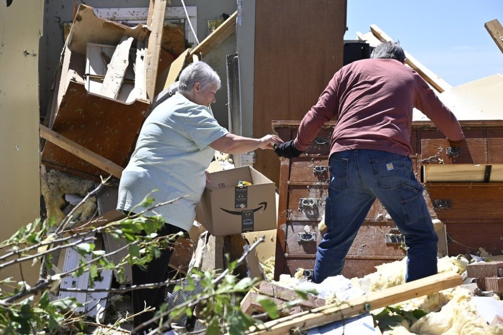 Don Allen, right, hands Doris Hensley medication that they are retrieving from the remains of her home following severe weather last night in London, Ky., Saturday, May 17, 2025. (AP Photo/Timothy D. Easley)