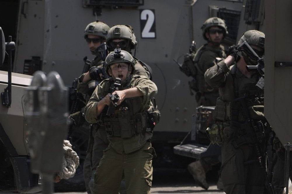 An Israeli soldier points his weapon during a military raid in the West Bank city of Nablus, Tuesday, June 10, 2025. (AP Photo/Majdi Mohammed)