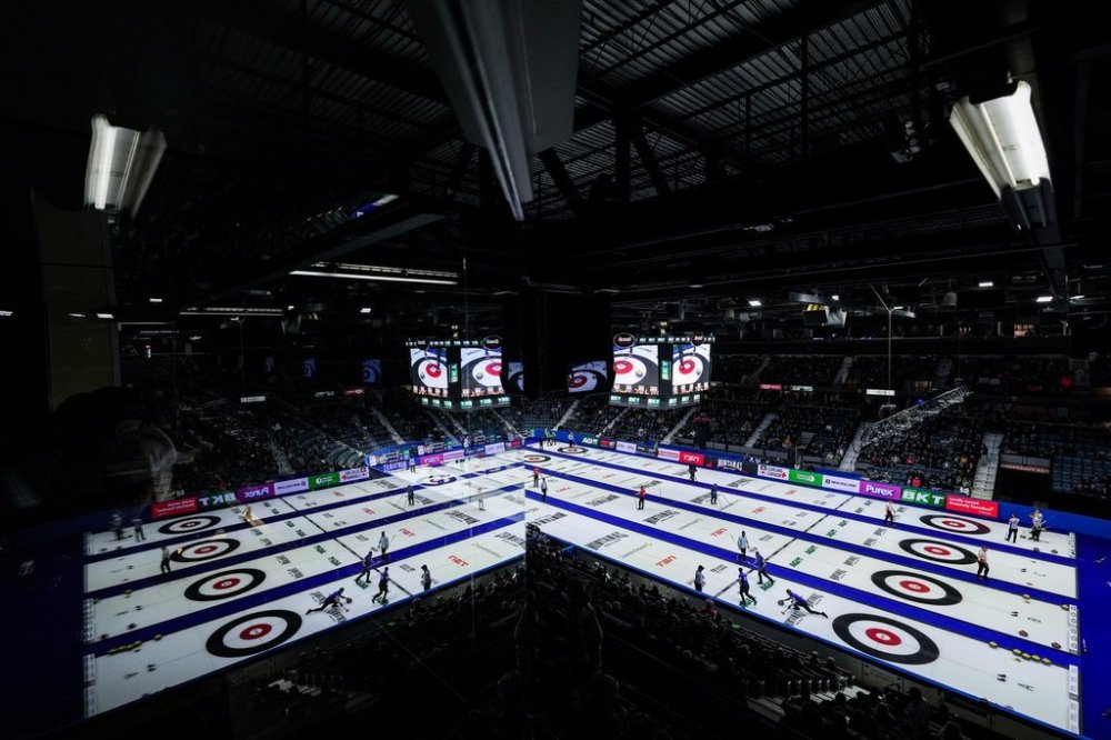 Reflected in a window of an arena suite, Alberta-Sluchinski second Kerr Drummond, bottom right, delivers a rock while playing Quebec during the Brier, in Regina, on Wednesday, March 6, 2024. THE CANADIAN PRESS/Darryl Dyck