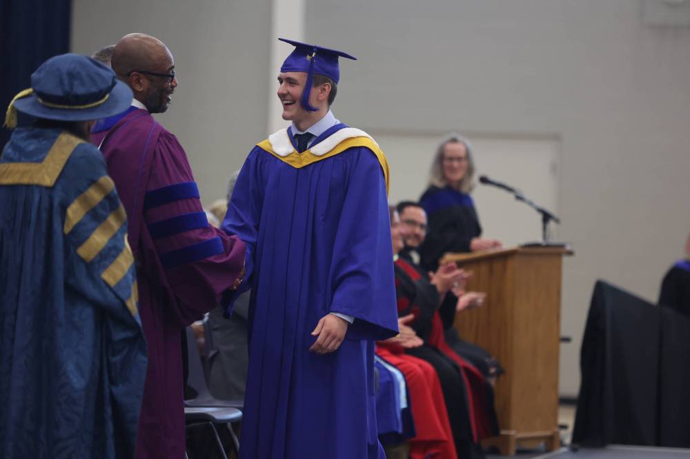 Political science major Brody Burr shakes hand with Brandon University acting president Kofi Campbell during the final convocation on Friday afternoon.