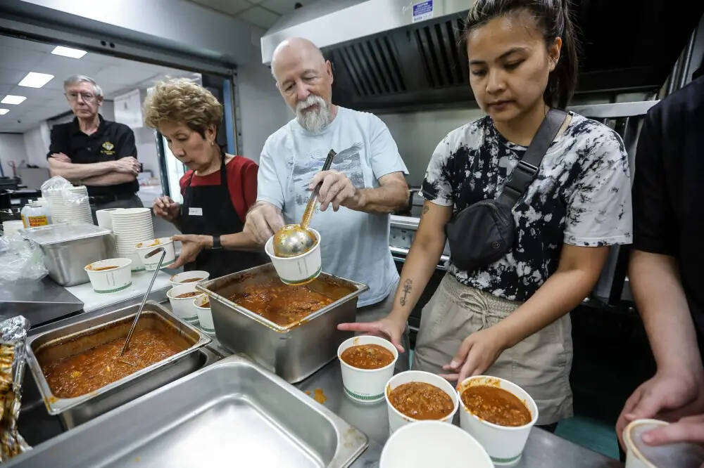 Ulysse Poirier, from left, Sally Bader, Bob, and Angela Daet prepare a meal for fire evacuees who are being housed at Century Arena in Winnipeg on Sunday. (John Woods/Winnipeg Free Press)