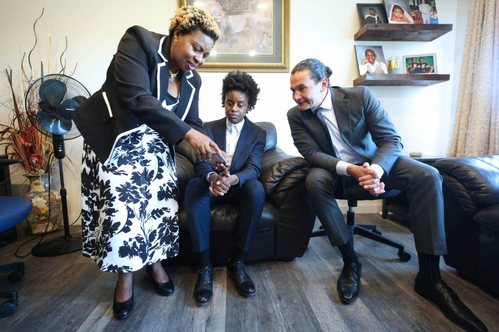 Helen Onuke (left), the mother of Neelin student Chinonso Onuke, shows pictures of her son's wounds to Manitoba Health Minister and Deputy Premier Uzoma Asagwara and Manitoba Premier Wab Kinew during a quiet visit at the Onuke family home near Sprucewoods on Thursday. (Photos by Matt Goerzen/The Brandon Sun)