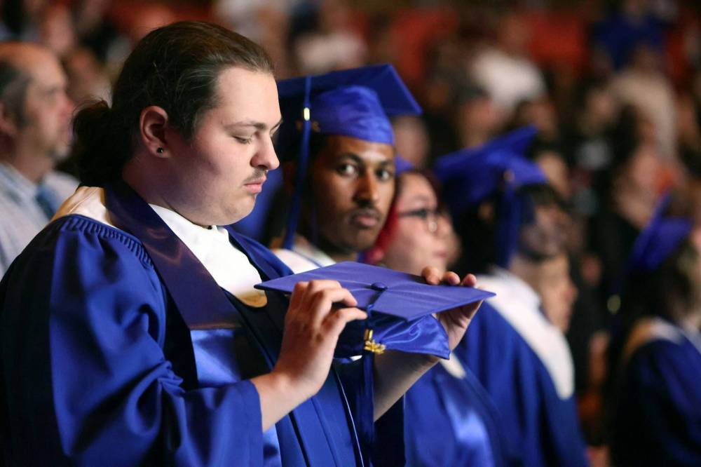 Graduate Caiden Loane looks at his cap during the start of his Prairie Hope High School graduation ceremony in Brandon on Thursday. Loane was one of 54 graduates from the school. (Alex Lambert/The Brandon Sun)