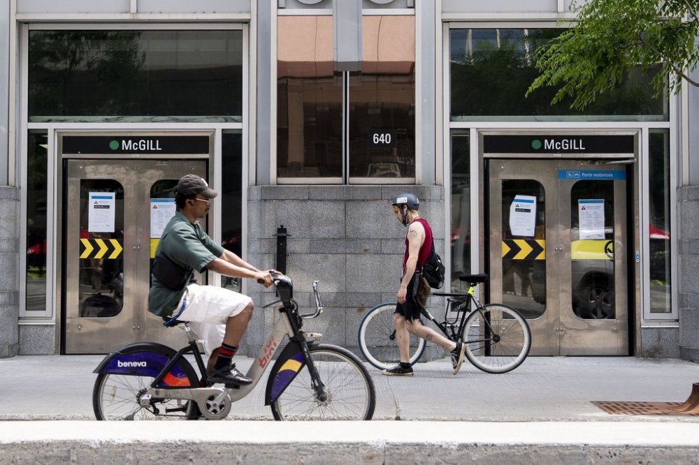 People on bikes pass by the locked doors of the McGill subway entrance, in Montreal on Wednesday, June 11, 2025. THE CANADIAN PRESS/Christopher Katsarov