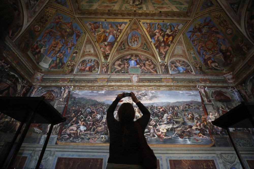 FILE - A visitor admires a Raphael Room inside the Vatican Museums at the Vatican, on May 3, 2021. (AP Photo/Alessandra Tarantino, File)