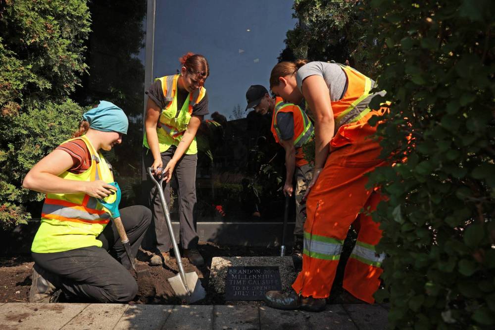 City of Brandon workers dig up the time capsule outside city hall on Friday. (Tim Smith/The Brandon Sun)