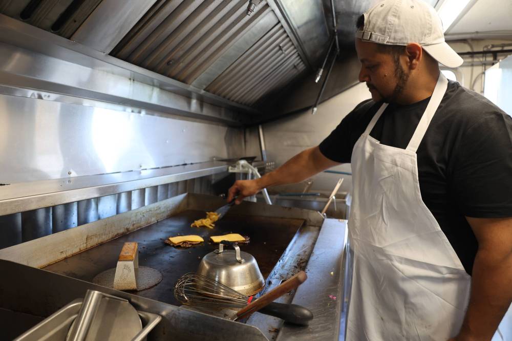 Ben grills up a smash burger at Los Brothers Street Food on 10th Street in Brandon on Wednesday.