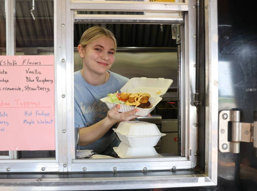 Alyx Delaloy, an employee at her grandfather’s restaurant — Uncle Tom’s Burgers in Neepawa — holds up the Nach ur Mama burger.