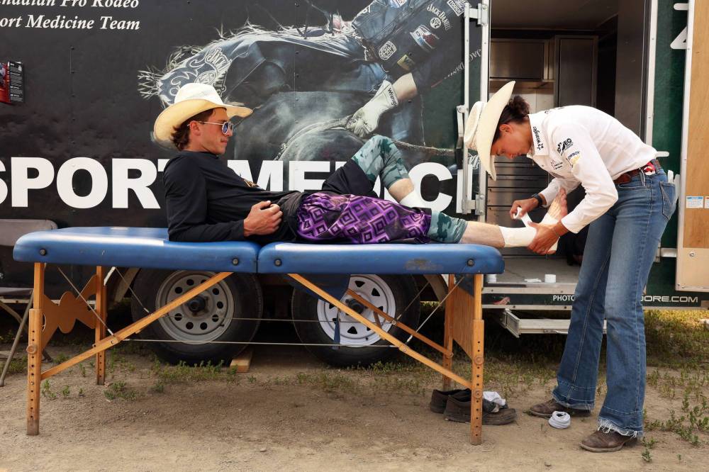 Bullfighter Cassidy Cairns of Maryfield, Sask., has his ankles taped up by Manon Lafreniere, a certified athletic therapist with the Canadian Pro Rodeo Sport Medicine Team. (Tim Smith/The Brandon Sun)