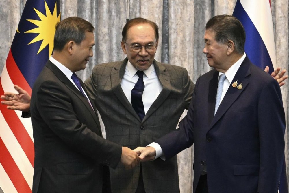 Cambodia's Prime Minister Hun Manet, left and Thailand's acting Prime Minister Phumtham Wechayachai, right shake hands as Malaysia's Prime Minister Anwar Ibrahim gestures after talks on a possible ceasefire between Thailand and Cambodia in Putrajaya, Malaysia, Monday, July 28, 2025. (Mohd Rasfan/Pool Photo via AP)