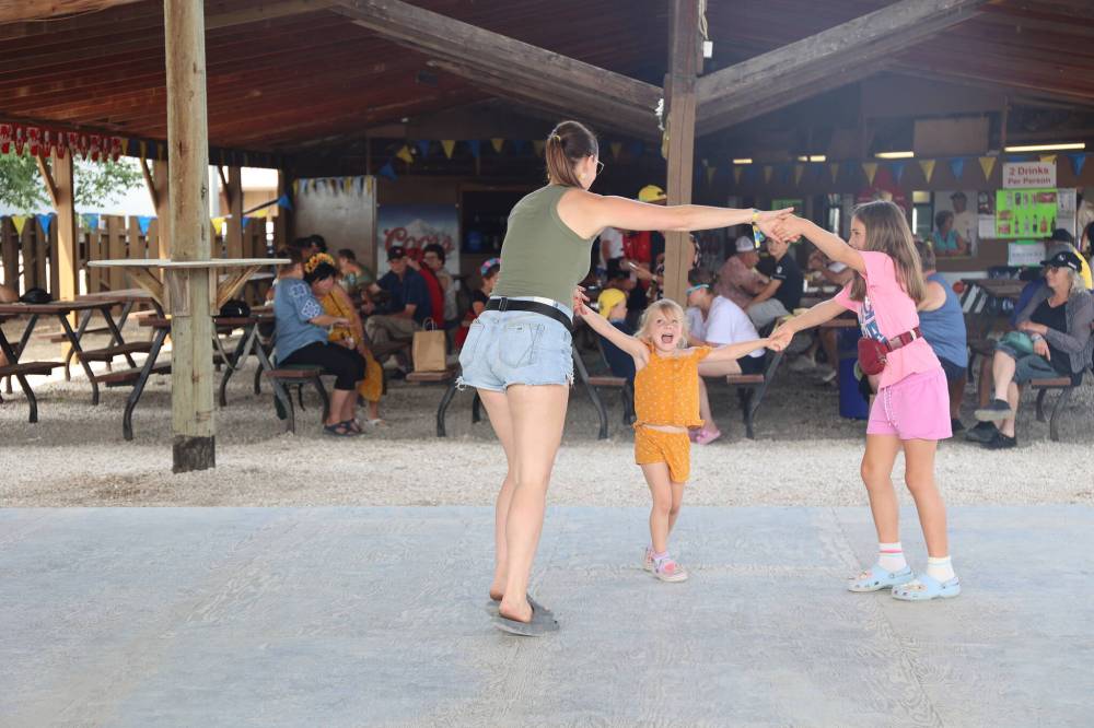 Alexa Barrett (left) dances with daughter Daciana Klassen and a guest during the performances of the Tyt I Tam band on Saturday afternoon. (Abiola Odutola/The Brandon Sun)