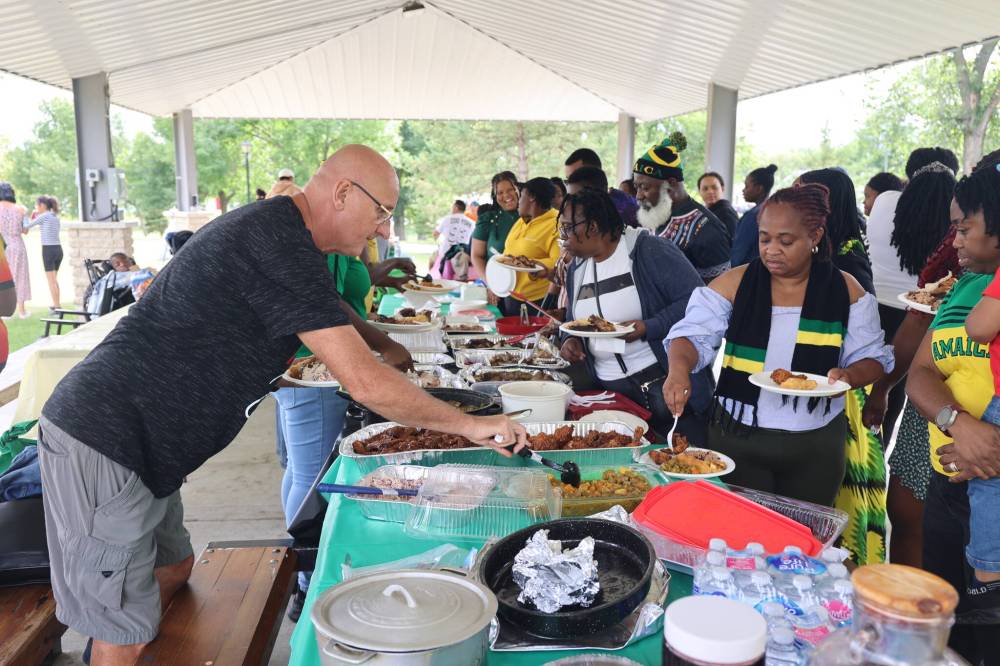 The Westman Jamaican Community and guests take different Jamaican foods from trays displayed during the annual Belly Business gathering.