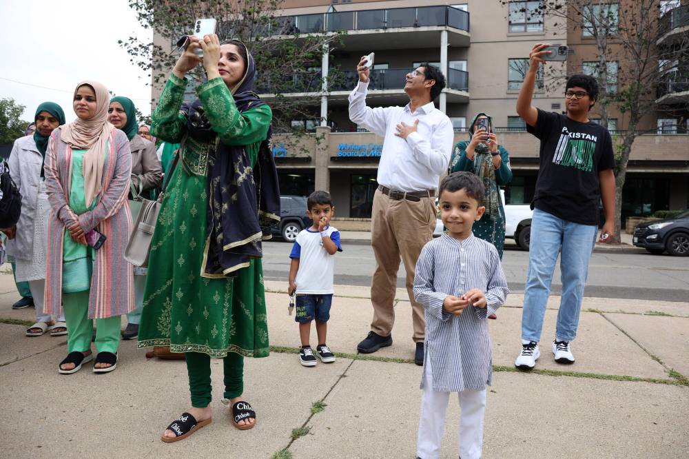 Members of Brandon’s Pakistani community take photos as the Pakistan flag is raised on Thursday.
