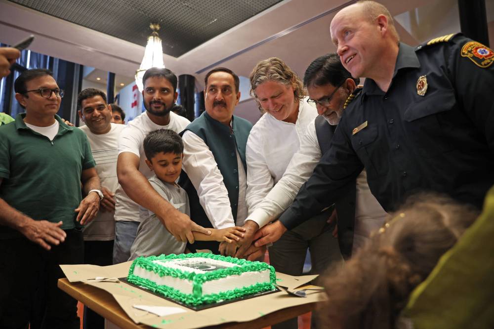 Fawcett cuts a cake along with members of the Pakistani community on Thursday at city hall.