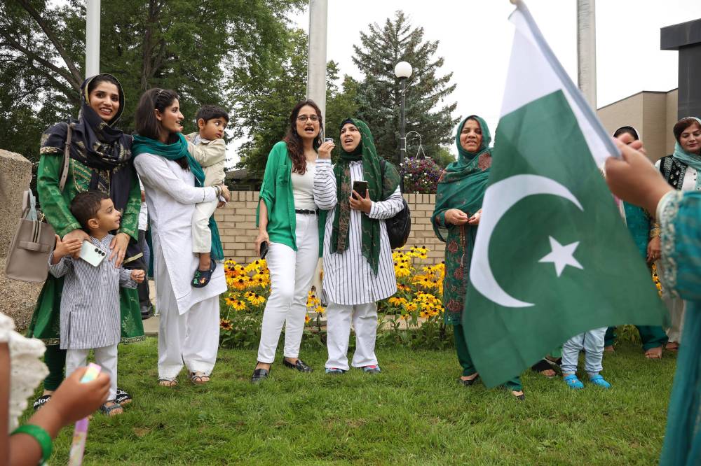Mehjabeen Musharraf and Madiha Awan lead fellow members of Brandon’s Pakistani community in singing the patriotic song “Dil Dil Pakistan” after raising the Pakistan flag outside Brandon City Hall on Thursday to celebrate Pakistan’s Independence Day. (Photos by Tim Smith/The Brandon Sun)