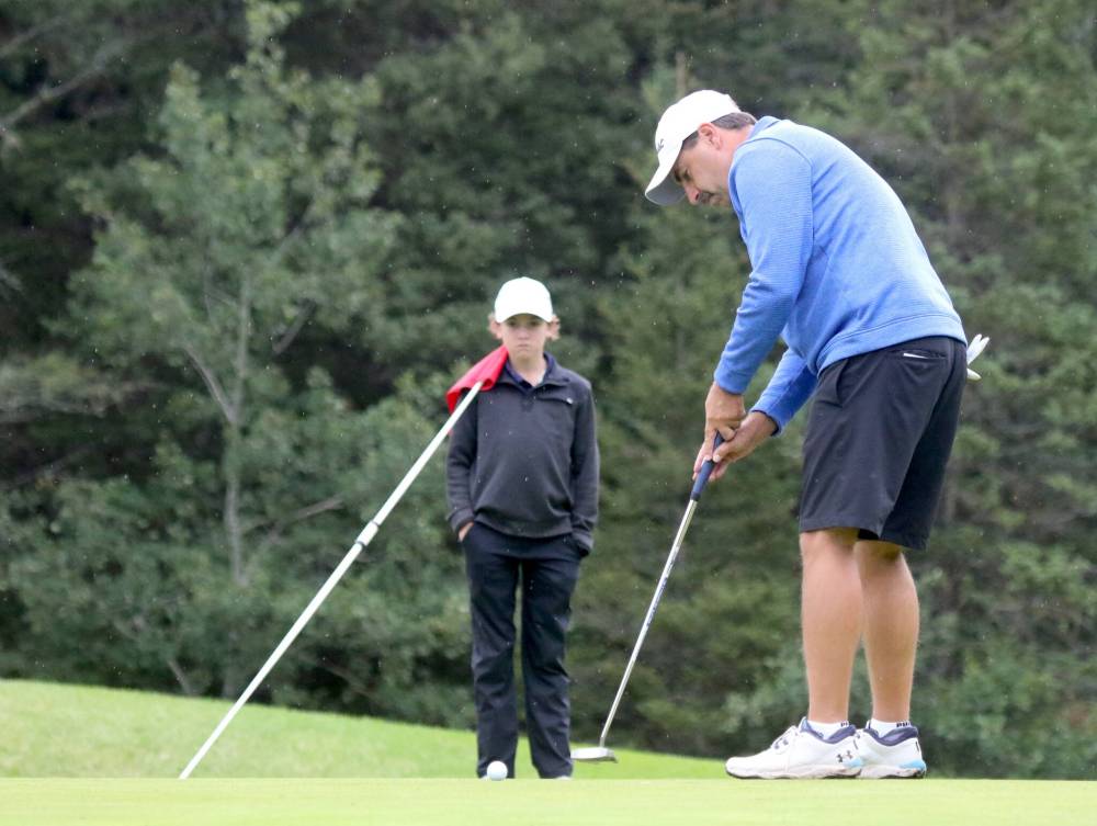Nolan Tutkaluk, right, rolls in one of his six birdies on Sunday as his son and caddie Austin looks on. (Thomas Friesen/The Brandon Sun)