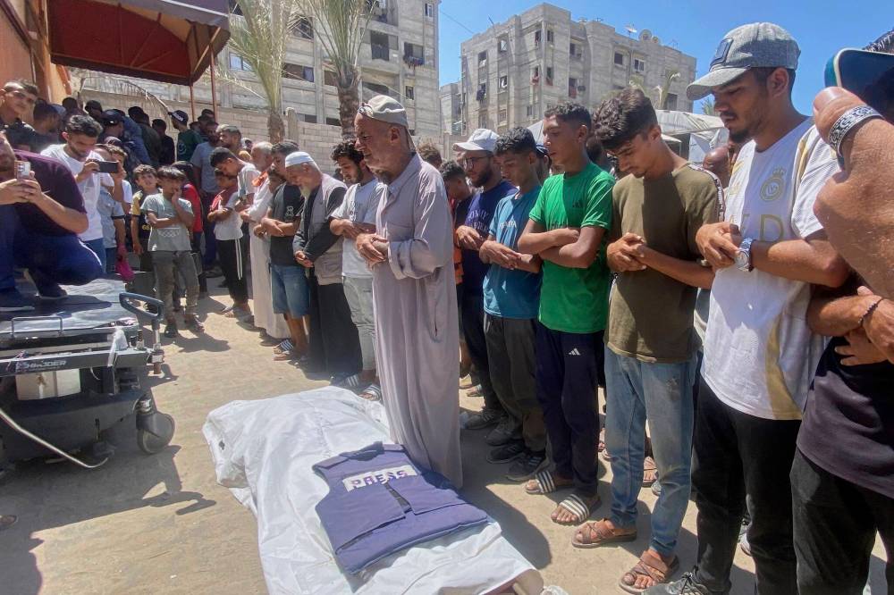 In this family handout photo, Riyad Dagga (centre) and other relatives and friends pray over the body of his daughter, freelance journalist Mariam Dagga, 33, during her funeral after she was killed in a double Israeli strike on Nasser Hospital in Khan Younis, southern Gaza Strip on Monday. (The Associated Press)