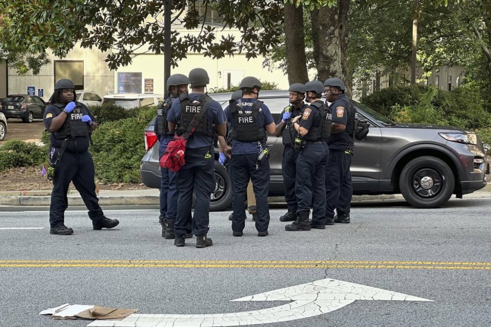 DeKalb County firefighters gather outside an Emory University medical building in Atlanta on Friday, Aug. 8, 2025. (AP Photo/Jeff Amy)
