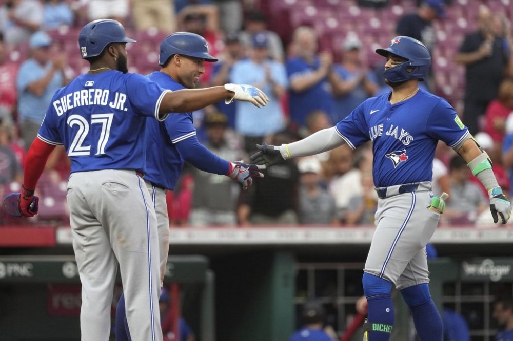 Toronto Blue Jays' Bo Bichette, far right, is congratulated by George Springer, centre, and Vladimir Guerrero Jr. (27) after hitting a three-run home run in the second inning of a baseball game against the Cincinnati Reds, Tuesday, Sept. 2, 2025, in Cincinnati. (AP Photo/Kareem Elgazzar)