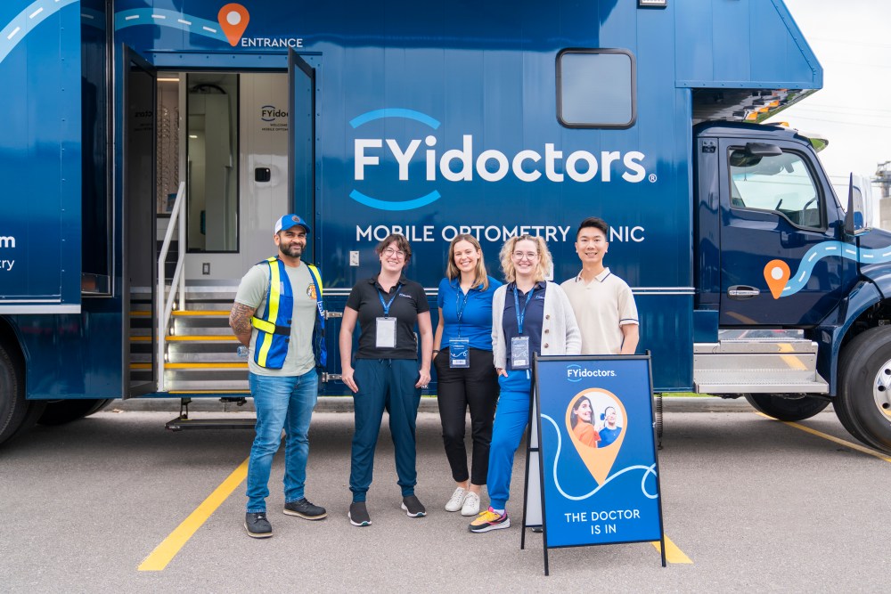 Goodwill Impact Centre in Calgary Talha Abbasi (left) and FYidoctors employees stand by the mobile clinic during the its recent outing in Calgary. The custom-built bus operates as a fully functional eye clinic on wheels. (Supplied)