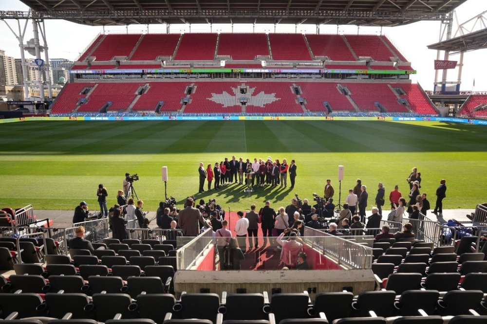 Politicians and stakeholders gather around a microphone during an announcement at Toronto's BMO Field on Friday, May 3, 2024, which revealed $104 million in federal funding for Toronto to host six games during the 2026 FIFA World Cup. THE CANADIAN PRESS/Chris Young