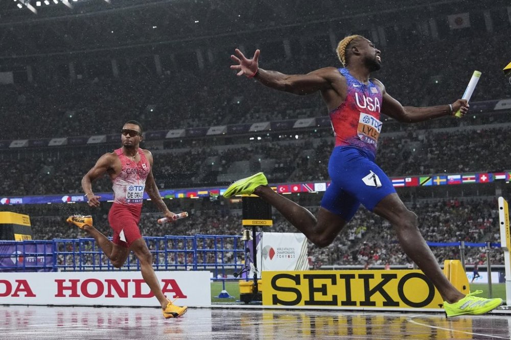 United States' Noah Lyles, right, crosses the finish line in first position, Canada's Andre De Grasse, silver, in the men's 4 X 100 metres relay final at the World Athletics Championships in Tokyo, Sunday, Sept. 21, 2025.(AP Photo/Bernat Armangue)