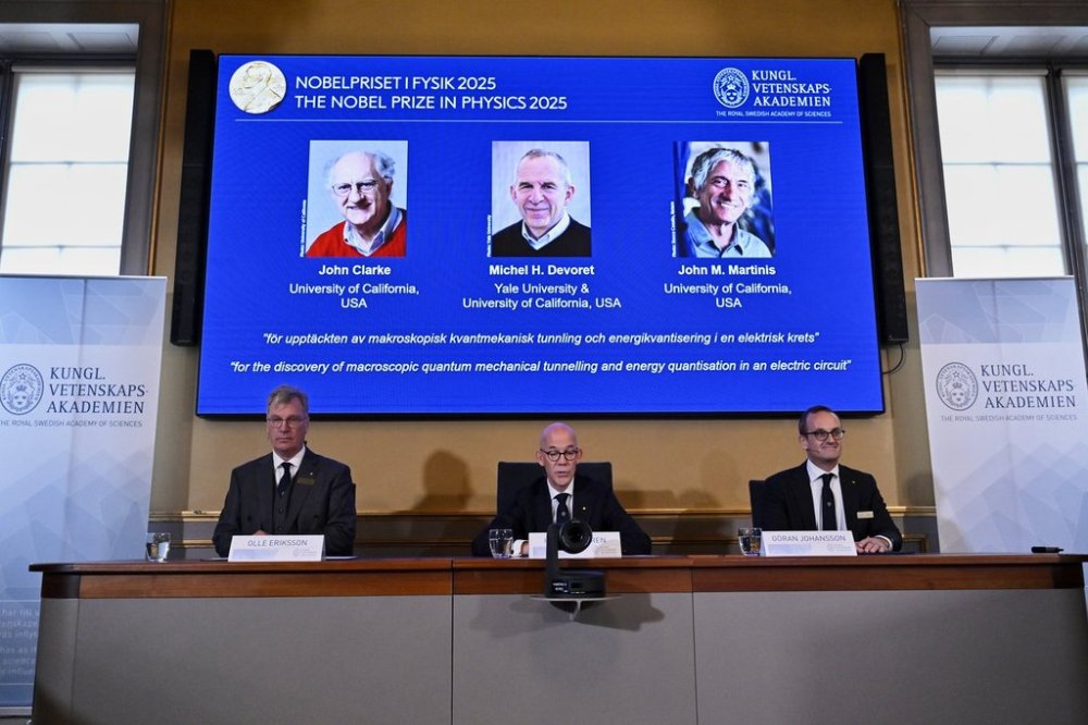 From left, Chair of the Nobel Committee for Physics Chair Olle Eriksson, Secretary General of the Swedish Academy of Sciences Hans Ellegren and Member of the Nobel Committee for Physics Goran Johansson announce John Clarke, Michel H Devoret and John M. Martinis, on screen behind, as the recipients the Nobel Prize in Physics, at the Nobel Assembly of the Karolinska Institutet, in Stockholm, Sweden, Tuesday, Oct. 7, 2025. (Christine Olsson/TT News Agency via AP)