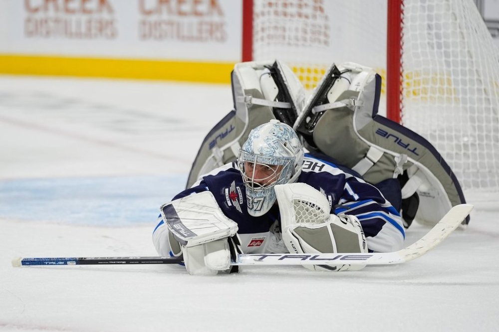 Winnipeg Jets goaltender Connor Hellebuyck (37) lays on the ground after stopping a shot during the third period of an NHL hockey preseason game against the Minnesota Wild, Tuesday, Sept. 30, 2025, in St. Paul, Minn. (AP Photo/Abbie Parr)
