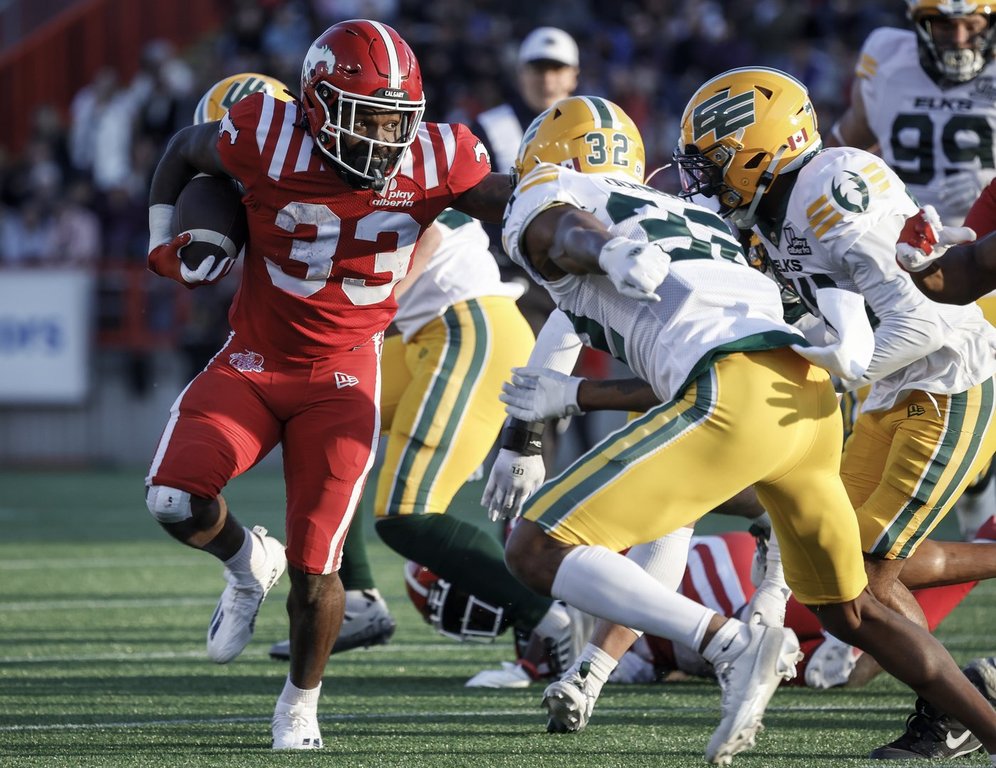 Edmonton Elks' Leonard Johnson, second right, closes in on Calgary Stampeders' Eno Benjamin during first half CFL pre-season football action in Calgary, Saturday, May 24, 2025.THE CANADIAN PRESS/Jeff McIntosh