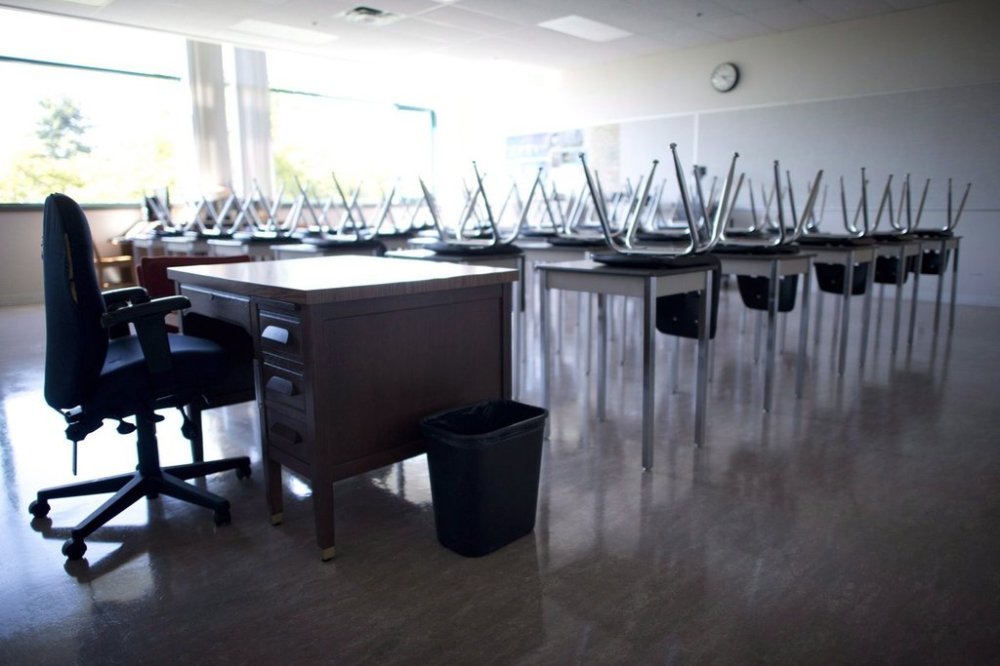 An empty teacher's desk is seen at the front of an empty classroom at McGee Secondary school in Vancouver on Sept. 5, 2014. THE CANADIAN PRESS/Jonathan Hayward
