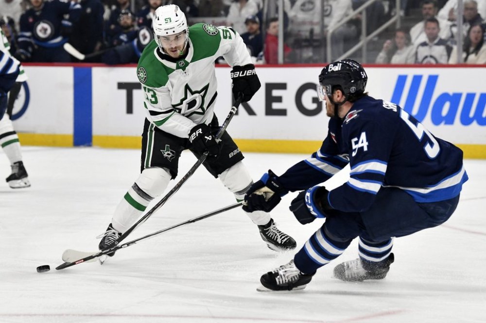 Winnipeg Jets' Dylan Samberg (54) knocks the puck away from Dallas Stars' Wyatt Johnston (53) during first period NHL playoff hockey action in Winnipeg, Thursday, May 15, 2025. THE CANADIAN PRESS/Fred Greenslade