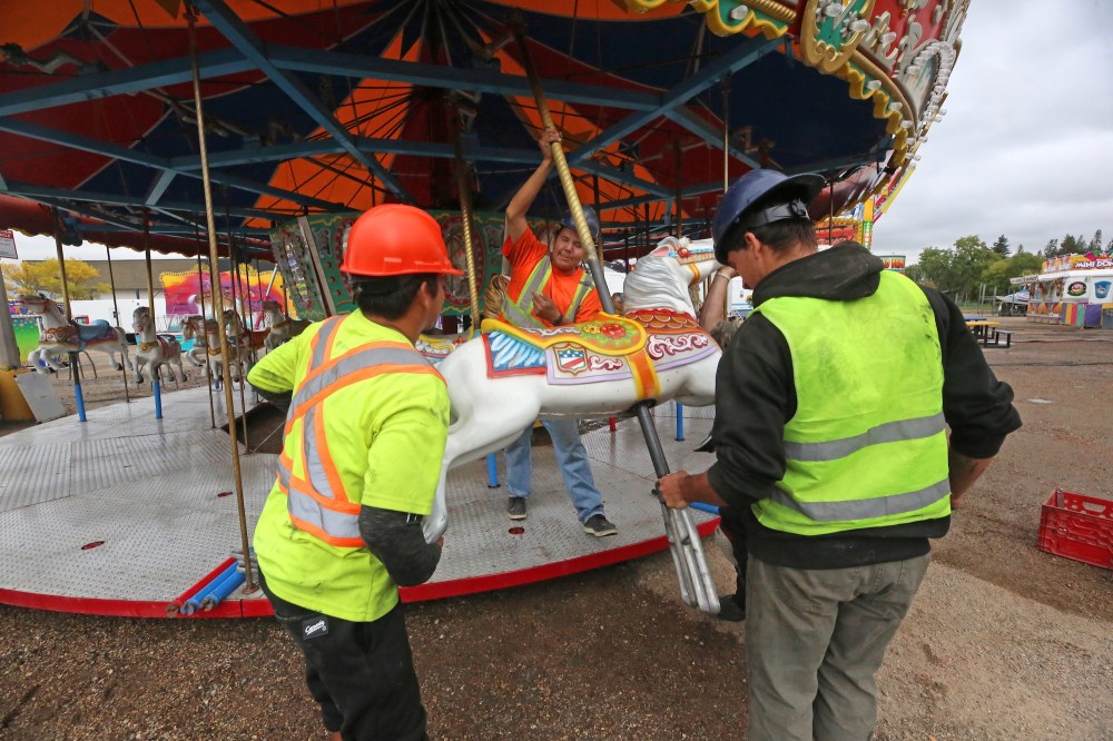 A work crew with Select Shows attaches a carousel horse to the Grand Carousel ride during a Thursday afternoon midway set up at the Keystone Centre grounds. Select Shows will hold its final show in Brandon this season, starting today for the Fall Fair. Gates open at 5 p.m. (Matt Goerzen/The Brandon Sun)