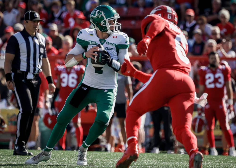 Saskatchewan Roughriders quarterback Trevor Harris, left, looks for a receiver as the Calgary Stampeders’ Derrick Moncrief closes in during CFL football action in Calgary on Aug. 23. Bruce Penton has pencilled in Roughriders versus Stampeders for the Western final. (The Canadian Press files)