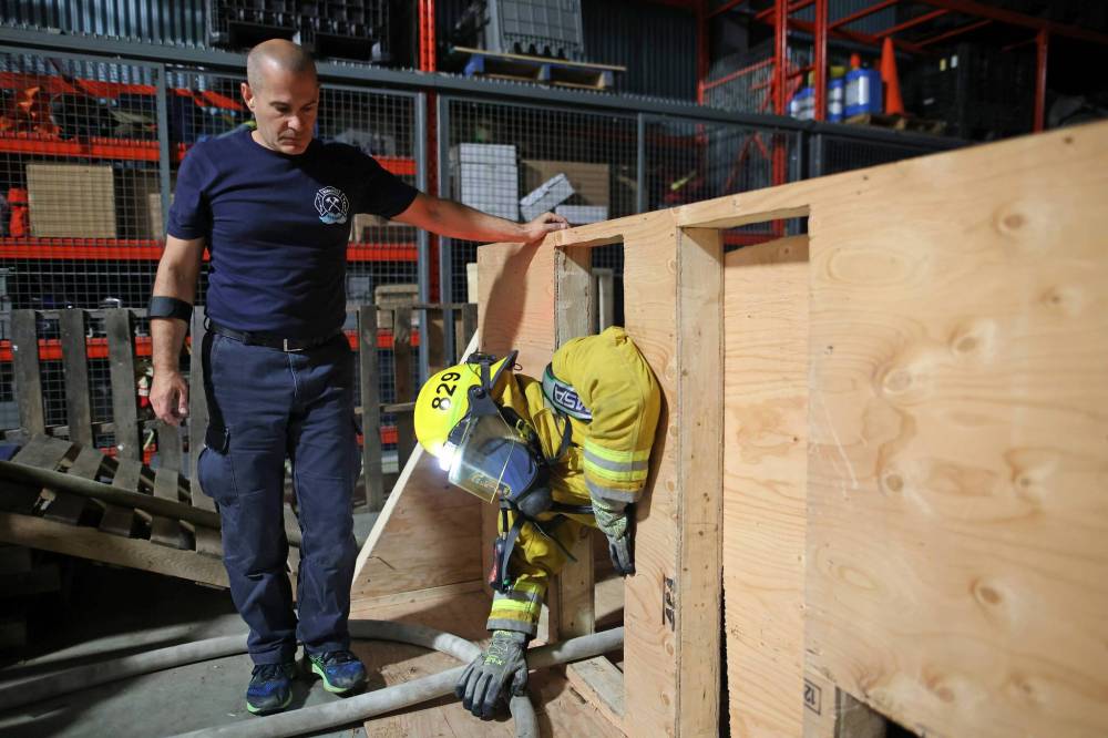 Peter Bowyer, a fire ground survival instructor, watches as Doucet emerges from the confidence course.