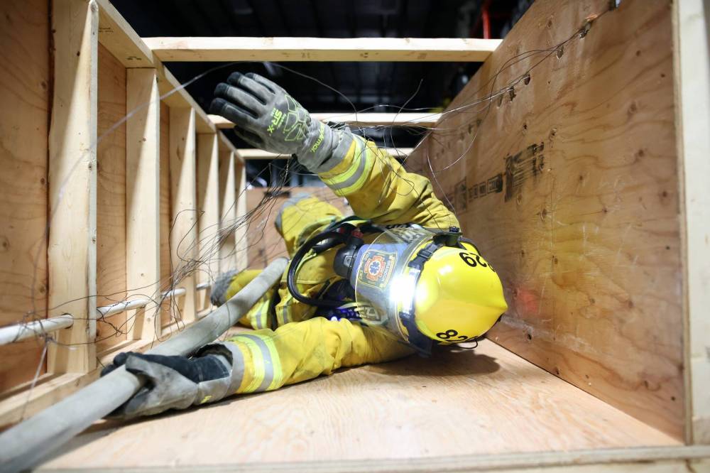 Alex Doucet, a fire training officer with the Ninette Fire Department, works his way through a confidence course in full fire gear and completely blindfolded as part of training at the Manitoba Emergency Services College during the Brandon Emergency Services Conference 2025 on Thursday. Ninety firefighters from different departments across the province took part in two days of training and courses. The confidence course simulated being a lost and disoriented firefighter separated from their crew during a fire. Each course participant had to navigate the obstacle course blind, while dealing with cramped spaces, obstacles and loud music and sounds, while following a hose line out of the course. The training is followed by the conference, which begins today and runs until Saturday, with speakers, a trade show and social events. (Tim Smith/The Brandon Sun)