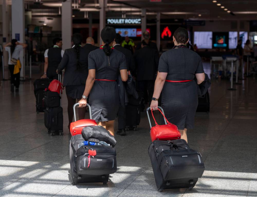 Air Canada flight attendants walk through Montreal-Pierre Elliott Trudeau International Airport in Dorval, Que., last month. (The Canadian Press files)