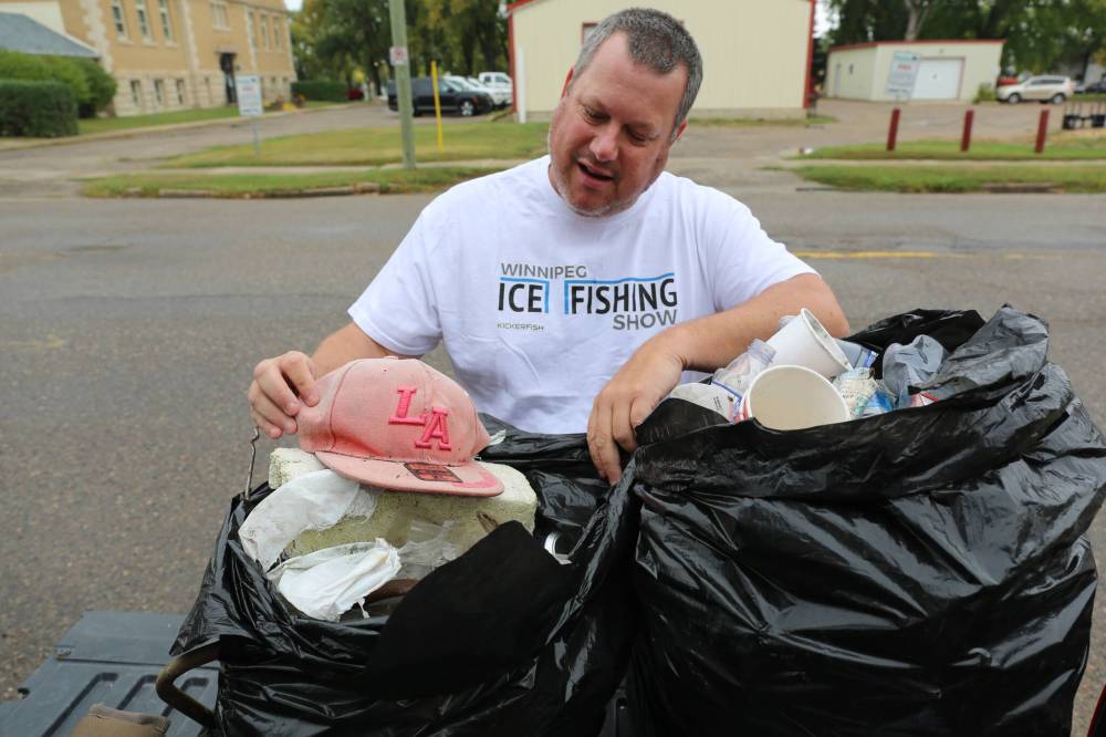 Dale Hutchings looks through the garbage that he and a friend picked up Wednesday evening along the Assiniboine River near the Manitoba Hydro generating station. (Michele McDougall/The Brandon Sun)