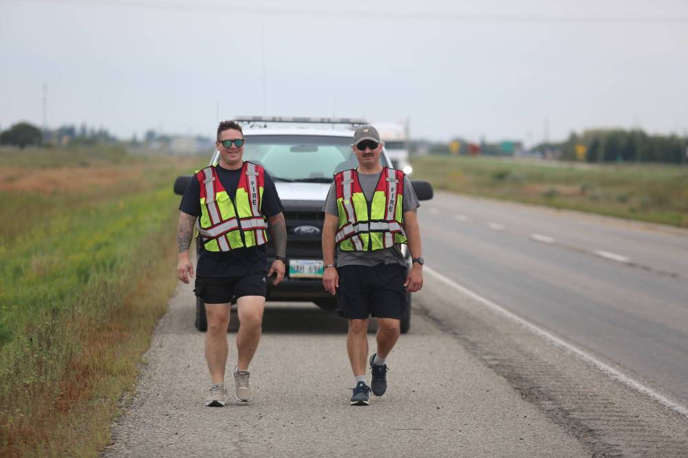 Manitoba Emergency Services College instructor and Carberry Fire captain Mike Sudak walks with former Winnipeg firefighter Andrew Cherkas (right) from Brandon to Carberry along the Trans-Canada Highway on Saturday afternoon. Cherkas walked from the Saskatchewan border earlier this week and has already passed through Virden, Oak Lake and Brandon to raise awareness and funds for firefighters struggling with mental health challenges. (Abiola Odutola/The Brandon Sun)