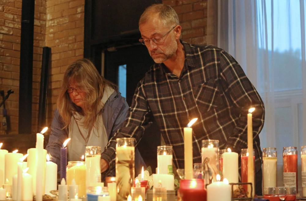 Two people add lit candles to a table at the front of the dining room at the Firehall Event Venue on Princess Avenue during a vigil for American conservative activist Charlie Kirk, who was shot to death earlier this month as he spoke to university students in Utah. The candlelight vigil drew about 250 mourners and supporters on Friday evening. (Photos by Matt Goerzen/The Brandon Sun)