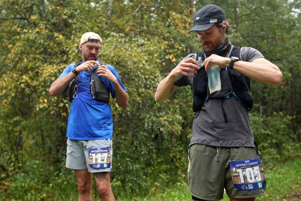 Matthew Holden and Jeffrey Chezick fill their water bottles at an aid station.