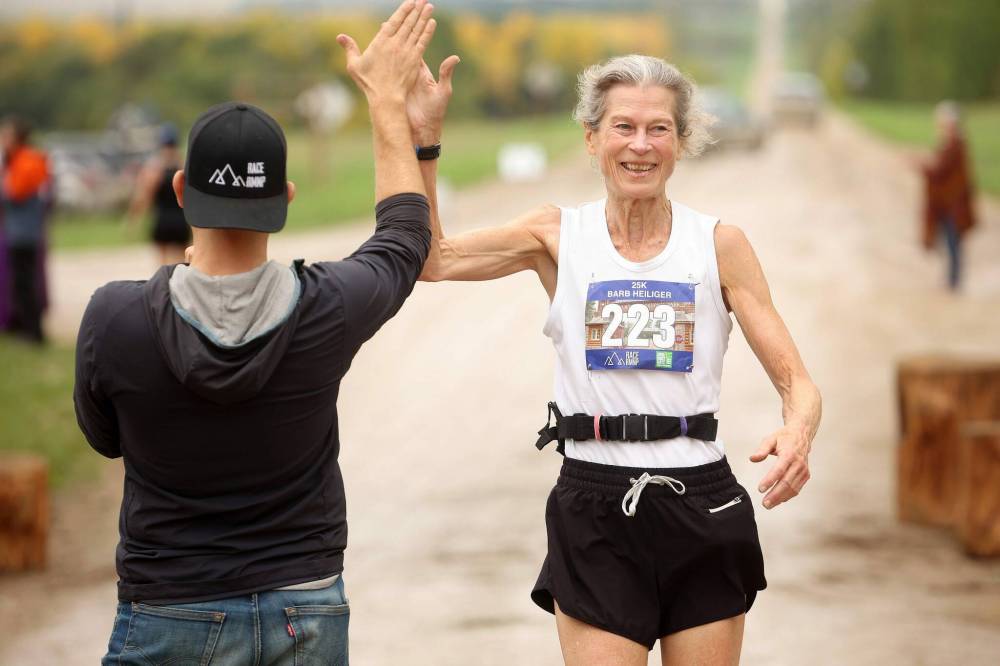 Barb Heiliger receives a high five and cheers as she crosses the finish line while competing in the 25 km category.