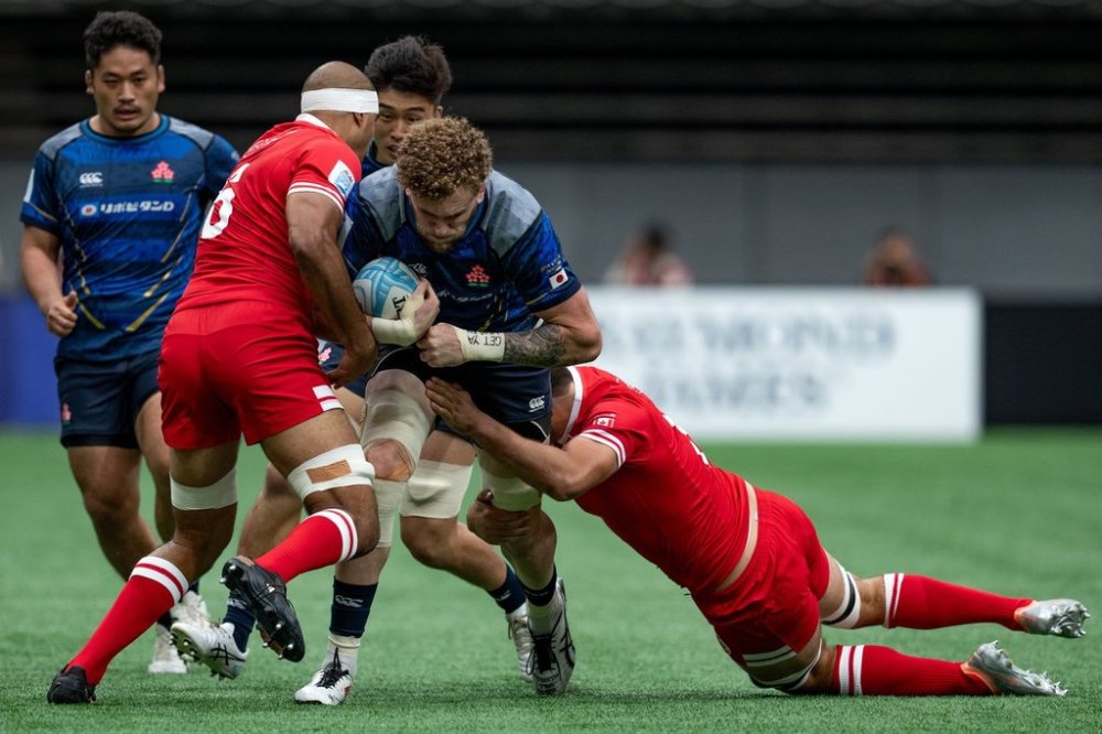 Japan's Warner Dearns runs the ball as Canada's Mason Flesch and Lucas Rumball tackle during the first half of Pacific Nations Cup rugby, in Vancouver, on Sunday, August. 25, 2024. THE CANADIAN PRESS/Ethan Cairns