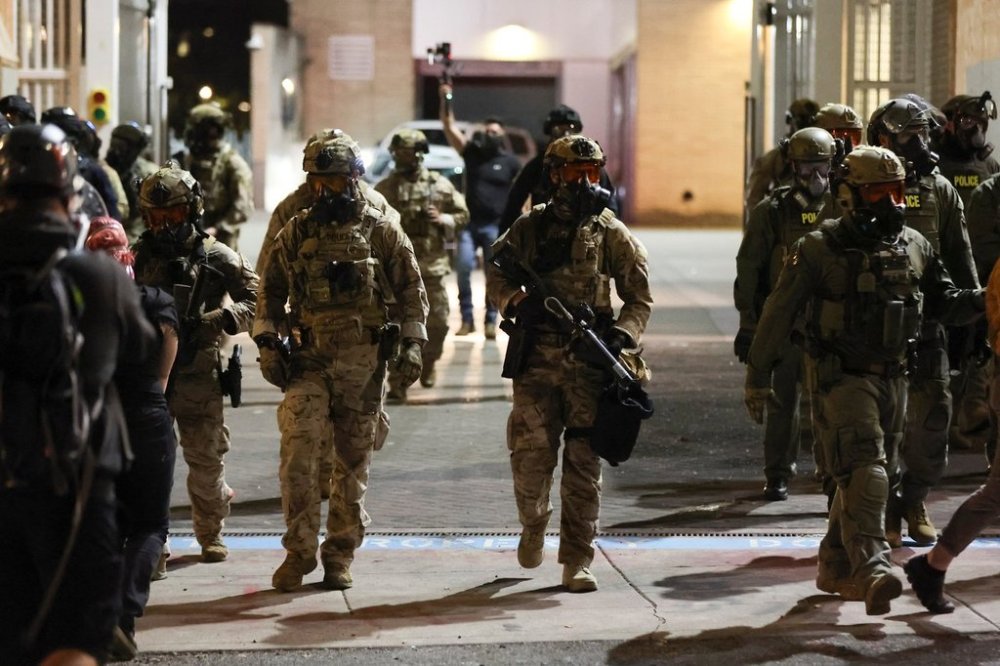 Federal agents walk into the street as people protest outside a U.S. Immigration and Customs Enforcement facility in Portland, Oregon, Friday, Oct. 3, 2025. (AP Photo/Amanda Loman)